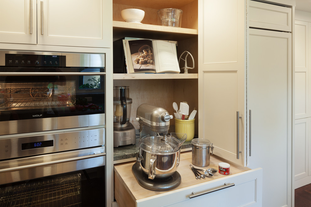 Large transitional galley medium tone wood floor open concept kitchen photo in Boston with an undermount sink, shaker cabinets, white cabinets, granite countertops, multicolored backsplash, stone slab backsplash, stainless steel appliances and a peninsula