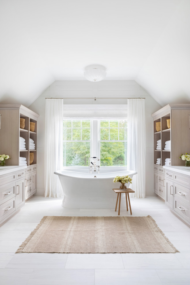 Photo of an expansive traditional master bathroom in New York with recessed-panel cabinets, light wood cabinets, a claw-foot tub, an alcove shower, a one-piece toilet, white tile, white walls, an integrated sink, marble benchtops, white floor, a hinged shower door and white benchtops.