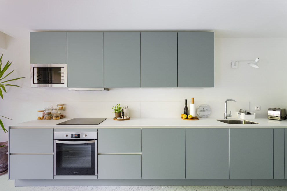 Mid-sized scandinavian single-wall open plan kitchen in Paris with an undermount sink, flat-panel cabinets, grey cabinets, quartzite benchtops, white splashback, stone tile splashback, stainless steel appliances, terrazzo floors, no island, multi-coloured floor and white benchtop.