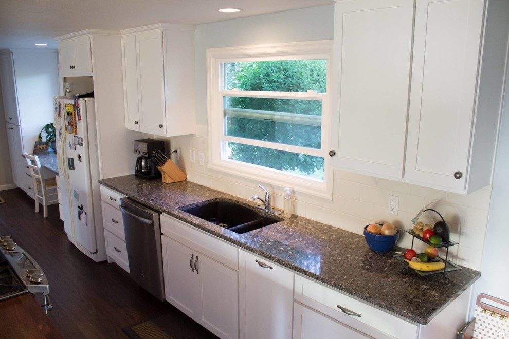 Mid-sized transitional galley dark wood floor and brown floor open concept kitchen photo with an undermount sink, shaker cabinets, white cabinets, wood countertops, white backsplash, porcelain backsplash, white appliances and an island