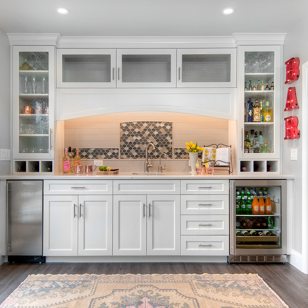 Inspiration for a mid-sized traditional single-wall wet bar in San Francisco with an undermount sink, shaker cabinets, white cabinets, quartz benchtops, multi-coloured splashback, mosaic tile splashback, vinyl floors, brown floor and white benchtop.