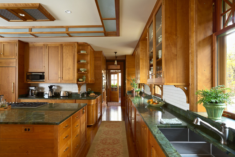 Photo of an expansive arts and crafts u-shaped separate kitchen in Minneapolis with an undermount sink, recessed-panel cabinets, medium wood cabinets, granite benchtops, white splashback, subway tile splashback, panelled appliances, medium hardwood floors and multiple islands.