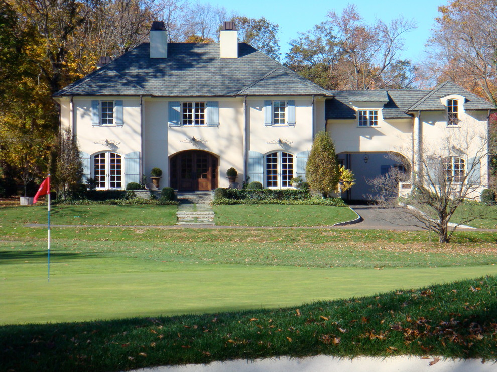 Large traditional two-storey stucco white house exterior in New York with a shingle roof.