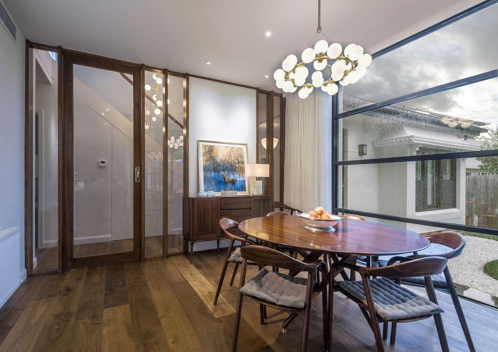 Photo of a mid-sized contemporary open plan dining in Melbourne with white walls, medium hardwood floors and brown floor.