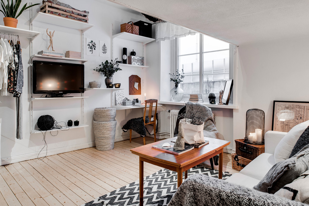 Design ideas for a small scandinavian open concept living room in Gothenburg with white walls, light hardwood floors, no fireplace and a freestanding tv.