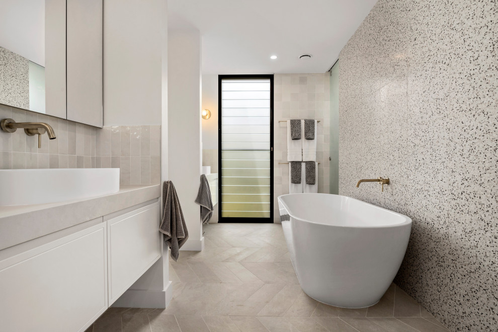 Design ideas for a beach style master bathroom in Sydney with flat-panel cabinets, white cabinets, a freestanding tub, beige tile, black and white tile, white walls, a vessel sink, beige floor and beige benchtops.
