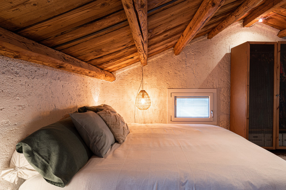 Inspiration for a medium sized rustic master loft bedroom in Venice with white walls, lino flooring, orange floors and exposed beams.