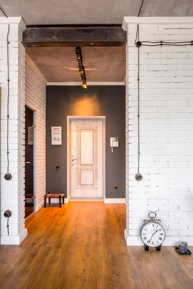 Photo of a mid-sized industrial entryway in Moscow with white walls and medium hardwood floors.