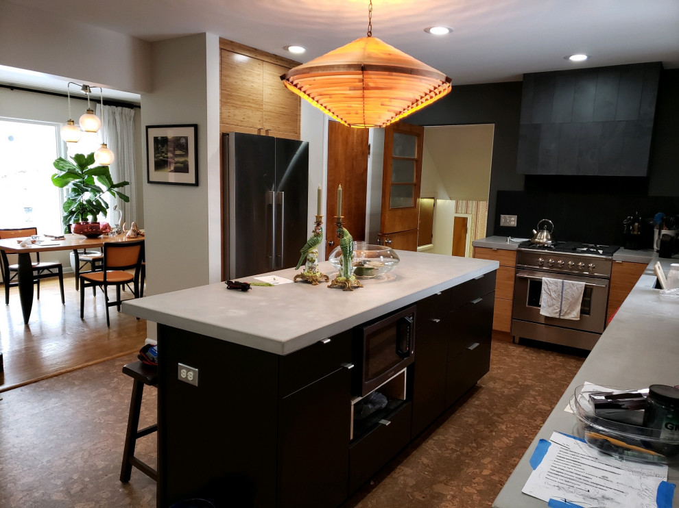 Photo of a midcentury kitchen in Grand Rapids with flat-panel cabinets, black cabinets, concrete benchtops, slate splashback and with island.