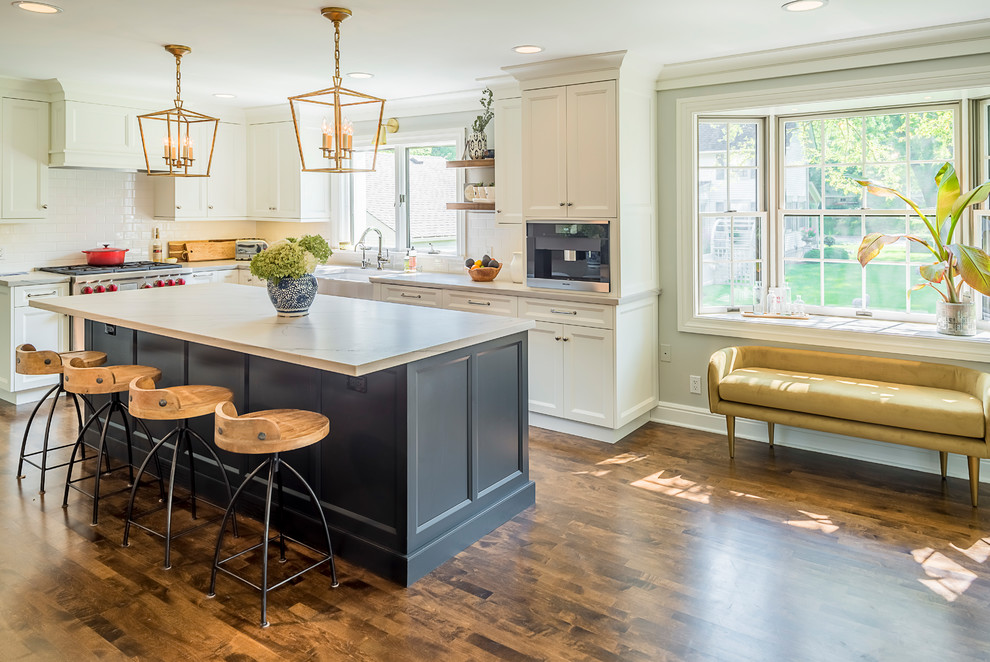 Inspiration for a large transitional l-shaped dark wood floor enclosed kitchen remodel in Chicago with recessed-panel cabinets, white cabinets, marble countertops, white backsplash, subway tile backsplash, stainless steel appliances and an island