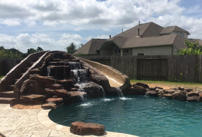Example of a mid-sized mountain style backyard tile and custom-shaped natural water slide design in Orange County