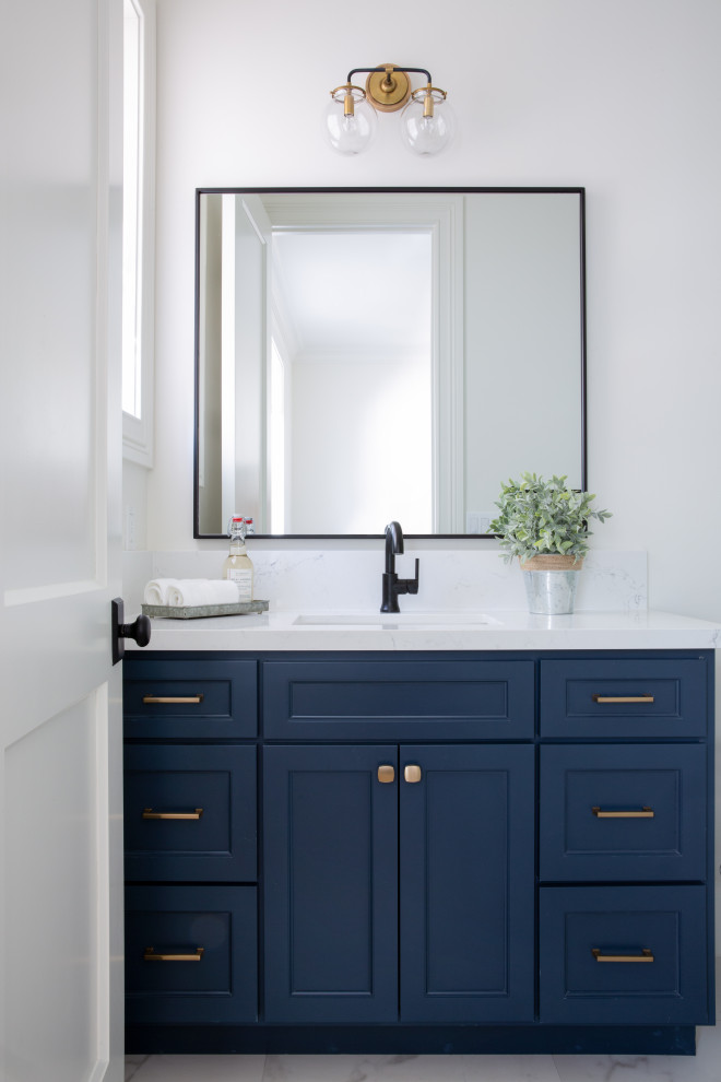 Cette photo montre une salle de bain chic avec un placard à porte shaker, des portes de placard bleues, un plan de toilette en quartz modifié et meuble-lavabo encastré.