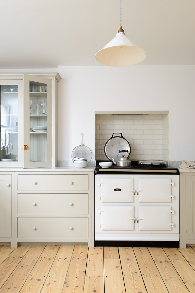 Inspiration for a mid-sized country u-shaped open plan kitchen in Sussex with a farmhouse sink, shaker cabinets, grey cabinets, marble benchtops, white splashback, subway tile splashback, white appliances, light hardwood floors and with island.