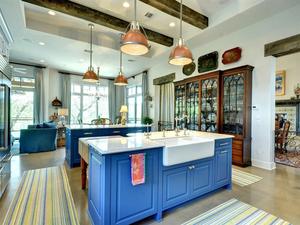 This is an example of a large eclectic l-shaped open plan kitchen in Austin with a farmhouse sink, raised-panel cabinets, blue cabinets, marble benchtops, stainless steel appliances, concrete floors, multiple islands and grey floor.