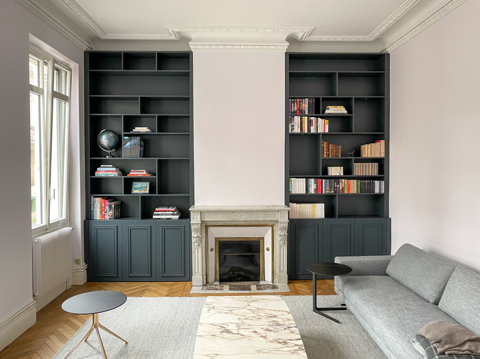 Mittelgroße, Fernseherlose Moderne Bibliothek mit weißer Wandfarbe, hellem Holzboden, Kamin, Kaminumrandung aus Stein und beigem Boden in Bordeaux