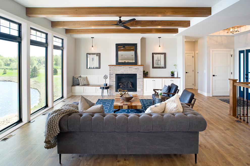 Mid-sized transitional open concept living room in Other with grey walls, laminate floors, a standard fireplace, a brick fireplace surround and brown floor.