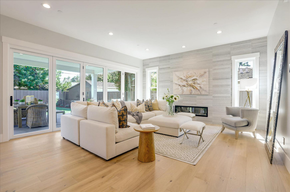 Family room - large coastal open concept light wood floor and brown floor family room idea in San Francisco with gray walls, a standard fireplace and a stone fireplace