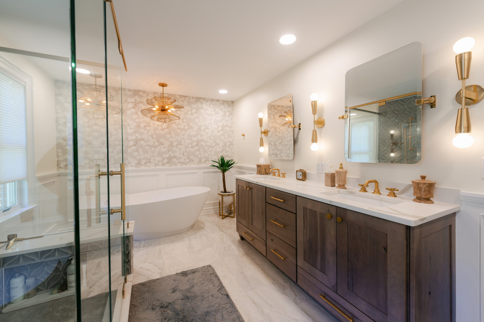 Пример оригинального дизайна: большая главная ванная комната в стиле неоклассика (современная классика) с фасадами в стиле шейкер, светлыми деревянными фасадами, отдельно стоящей ванной, открытым душем, унитазом-моноблоком, серой плиткой, керамической плиткой, бежевыми стенами, полом из цементной плитки, врезной раковиной, столешницей из искусственного кварца, белым полом, душем с распашными дверями, белой столешницей, тумбой под две раковины, напольной тумбой и панелями на стенах