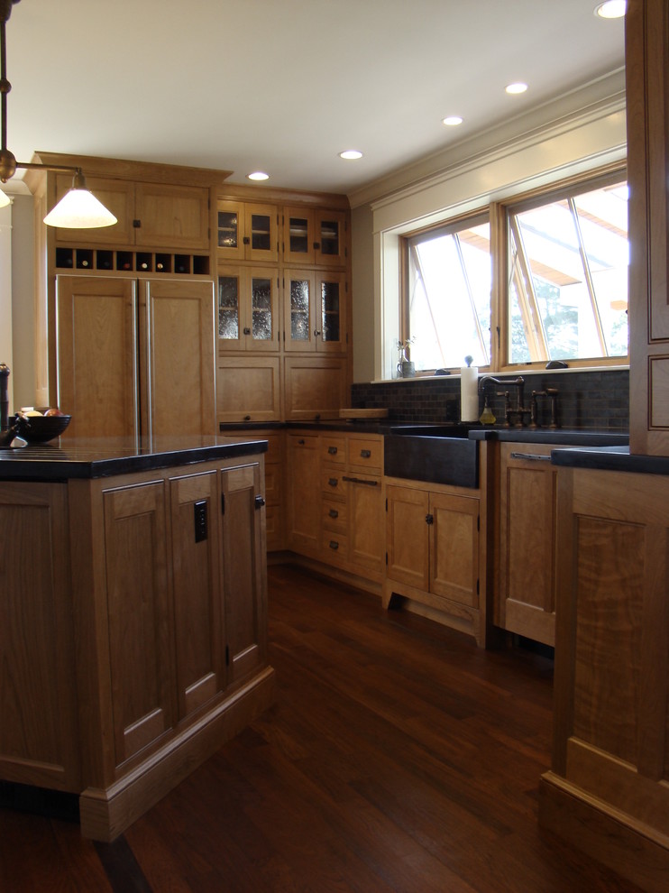 This is an example of a mid-sized arts and crafts l-shaped open plan kitchen in Portland Maine with a farmhouse sink, beaded inset cabinets, medium wood cabinets, concrete benchtops, grey splashback, stone tile splashback, panelled appliances, medium hardwood floors and with island.