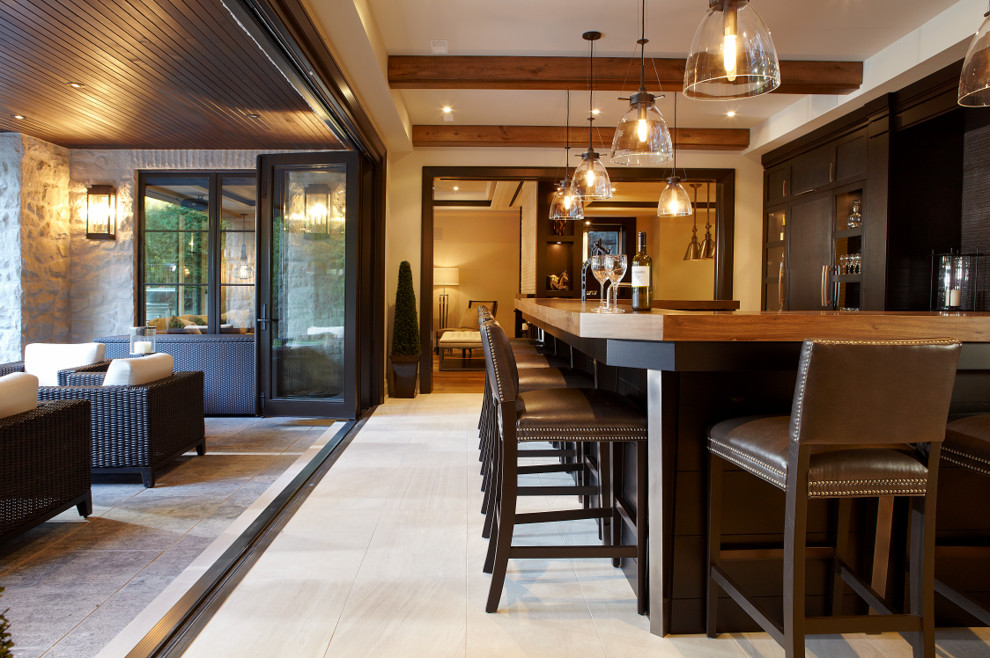 This is an example of a transitional u-shaped seated home bar in Toronto with dark wood cabinets, wood benchtops and brown benchtop.