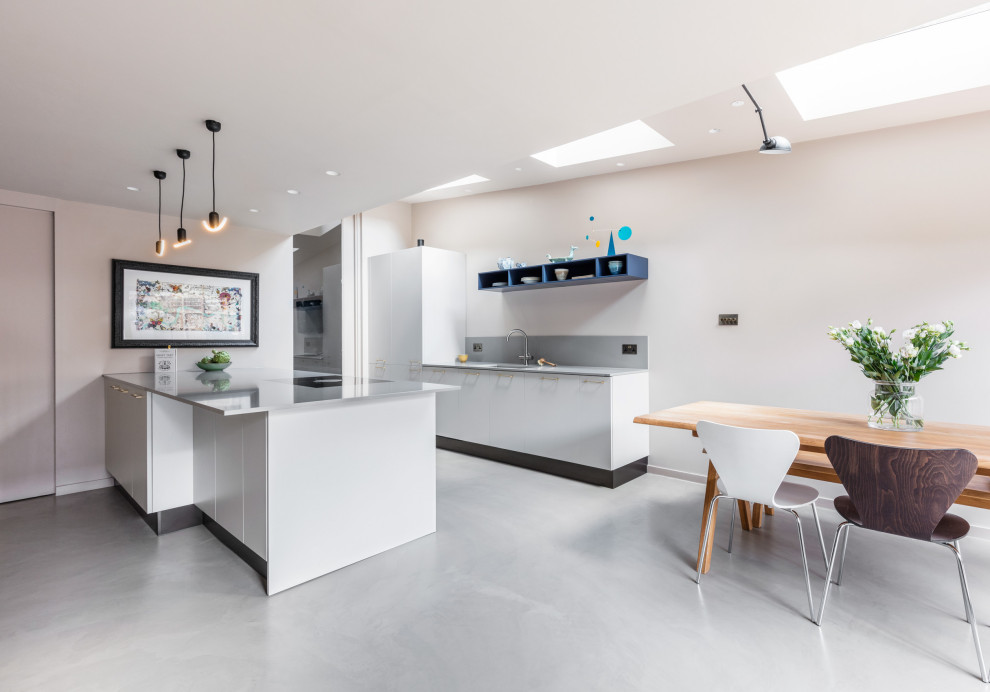 Mid-sized eclectic galley kitchen in London with an undermount sink, flat-panel cabinets, grey cabinets, quartzite benchtops, black appliances, concrete floors, with island, grey floor and grey benchtop.
