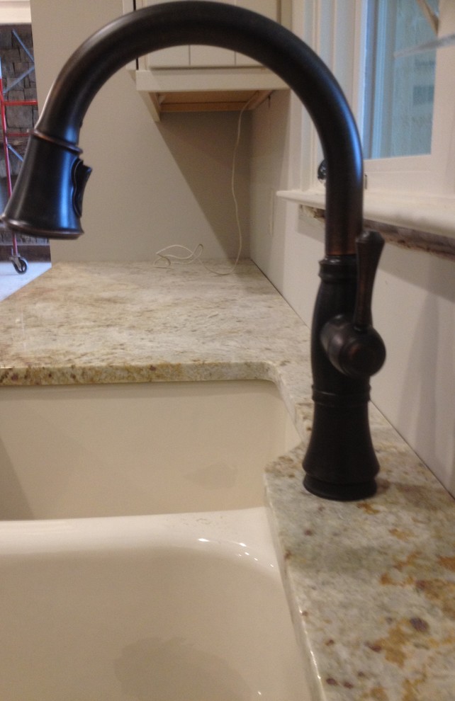 Example of a large mountain style u-shaped medium tone wood floor eat-in kitchen design with an undermount sink, recessed-panel cabinets, white cabinets, granite countertops, beige backsplash, stone tile backsplash, stainless steel appliances and an island