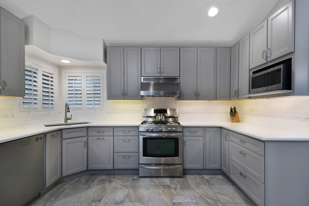 Inspiration for a mid-sized transitional u-shaped ceramic tile and gray floor kitchen remodel in Orlando with an undermount sink, beaded inset cabinets, gray cabinets, quartz countertops, white backsplash, subway tile backsplash, stainless steel appliances and no island