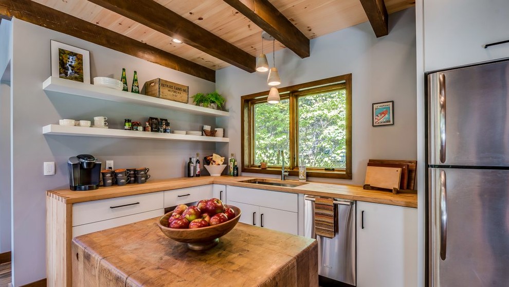 Small modern l-shaped eat-in kitchen in Boston with an undermount sink, flat-panel cabinets, white cabinets, wood benchtops, stainless steel appliances, ceramic floors, with island, brown floor and brown benchtop.