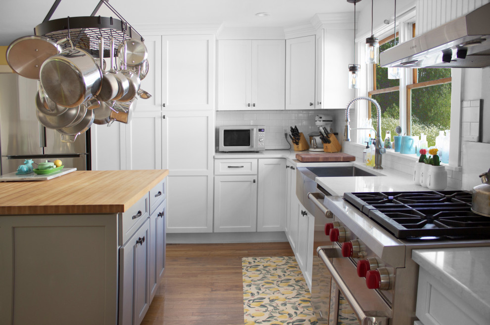Inspiration for a mid-sized country u-shaped eat-in kitchen in New York with a farmhouse sink, recessed-panel cabinets, white cabinets, quartz benchtops, white splashback, subway tile splashback, stainless steel appliances, medium hardwood floors, with island, brown floor and white benchtop.