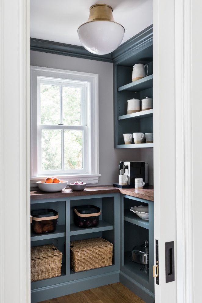 Traditional kitchen pantry in Boston with open cabinets, blue cabinets, wood benchtops, white splashback, light hardwood floors, with island and brown benchtop.