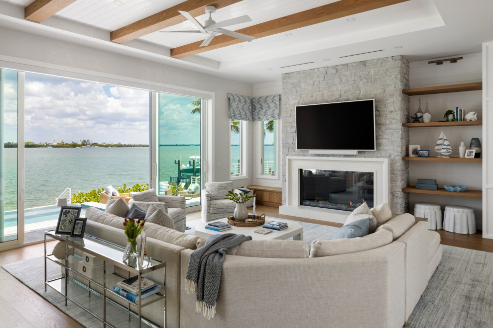 Beach style medium tone wood floor, brown floor, exposed beam, shiplap ceiling, tray ceiling and shiplap wall living room photo in Tampa with white walls, a standard fireplace and a wall-mounted tv