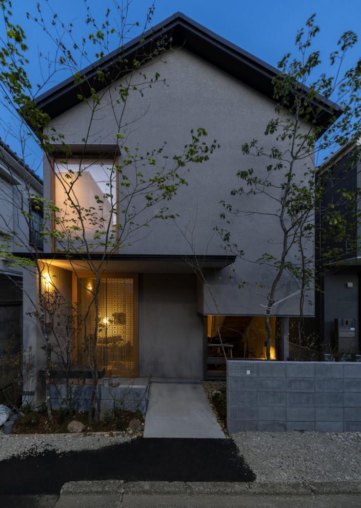 Mittelgroßes, Zweistöckiges Nordisches Einfamilienhaus mit Putzfassade, beiger Fassadenfarbe, Satteldach, Blechdach und schwarzem Dach in Tokio