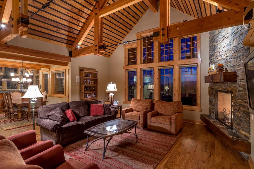 This is an example of a mid-sized country open concept living room in Other with medium hardwood floors, a corner fireplace, a stone fireplace surround, a wall-mounted tv and brown floor.