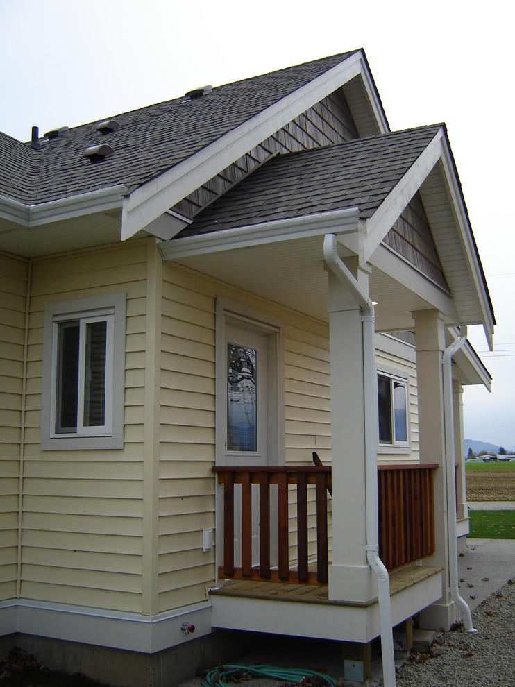 Inspiration for a small country one-storey yellow house exterior in Vancouver with vinyl siding, a gable roof and a shingle roof.