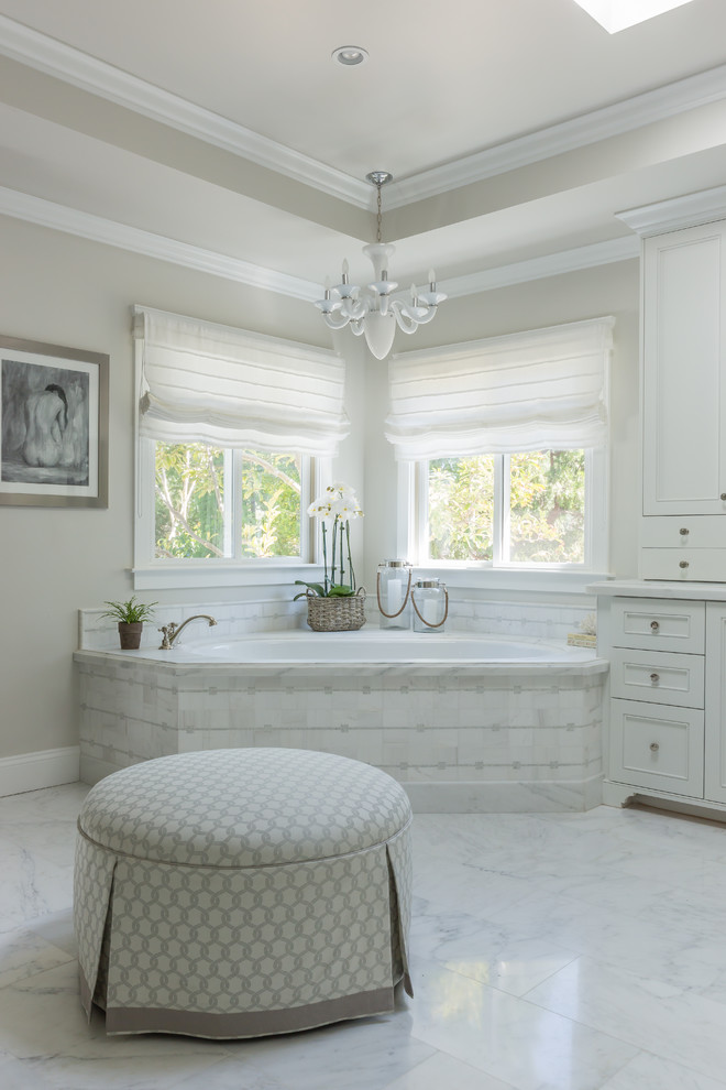 Photo of a large traditional master bathroom in Los Angeles with beaded inset cabinets, white cabinets, marble benchtops, a corner tub, white tile, mosaic tile and marble floors.