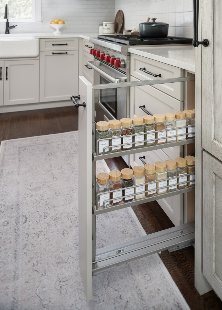 Inspiration for a mid-sized transitional l-shaped medium tone wood floor and brown floor eat-in kitchen remodel in New York with a farmhouse sink, shaker cabinets, beige cabinets, quartz countertops, white backsplash, porcelain backsplash, paneled appliances, an island and white countertops