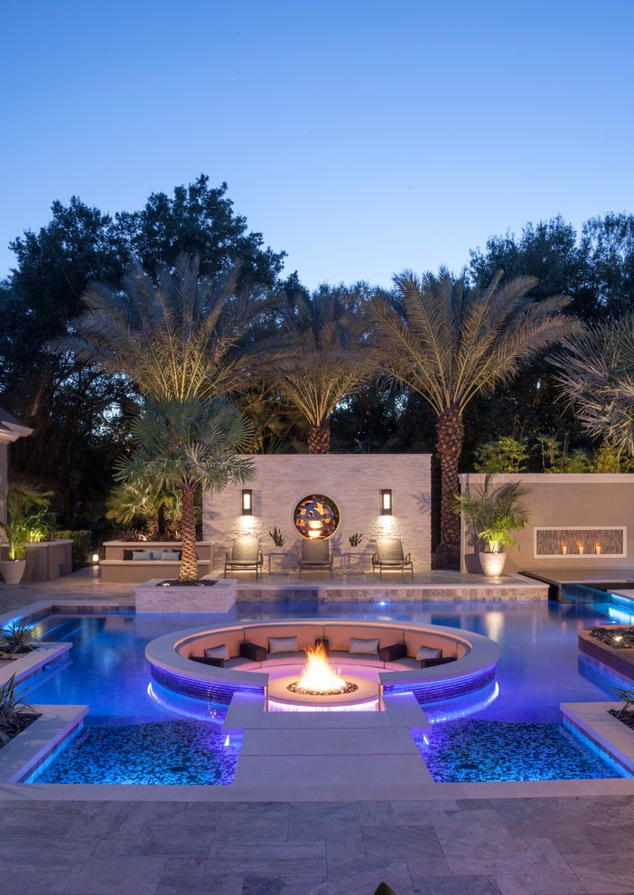 Inspiration for a large modern backyard custom-shaped pool in Tampa with natural stone pavers.