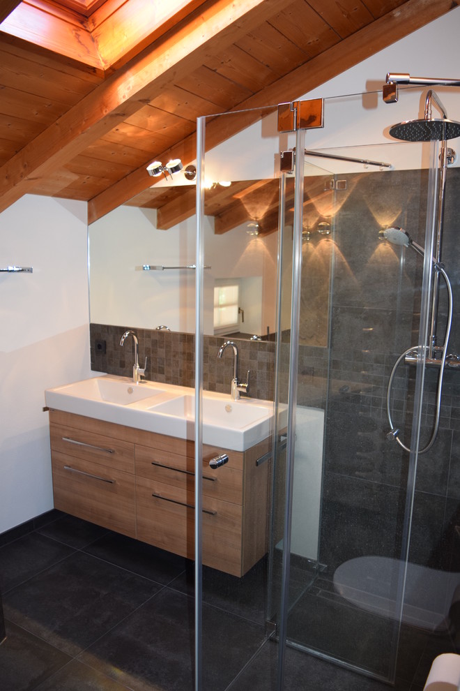 Photo of a small contemporary 3/4 bathroom in Munich with flat-panel cabinets, medium wood cabinets, a curbless shower, black tile, mosaic tile, white walls, cement tiles, an integrated sink, solid surface benchtops, black floor and a hinged shower door.