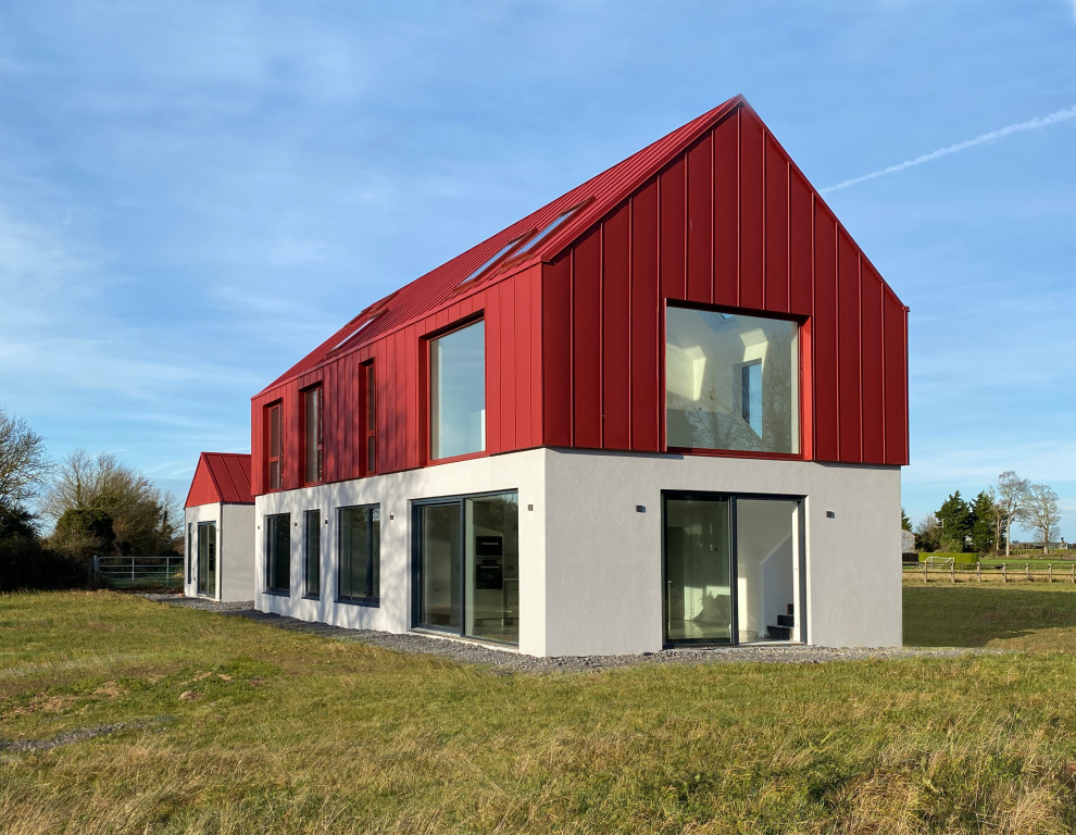Immagine della villa grande rossa moderna a due piani con rivestimento in metallo, tetto a capanna, copertura in metallo o lamiera e tetto rosso