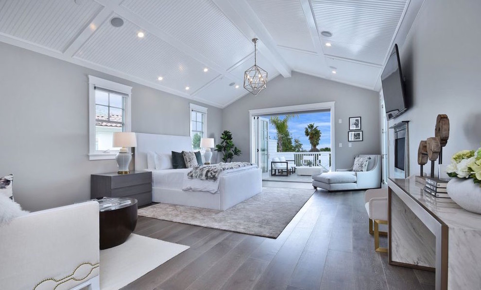Large contemporary master bedroom in Los Angeles with grey walls, medium hardwood floors, a standard fireplace, a metal fireplace surround and brown floor.