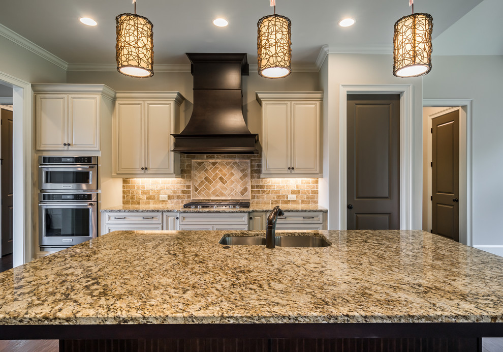 This is an example of a transitional eat-in kitchen in Atlanta with a drop-in sink, raised-panel cabinets, beige cabinets, granite benchtops, multi-coloured splashback, brick splashback, stainless steel appliances, dark hardwood floors and with island.