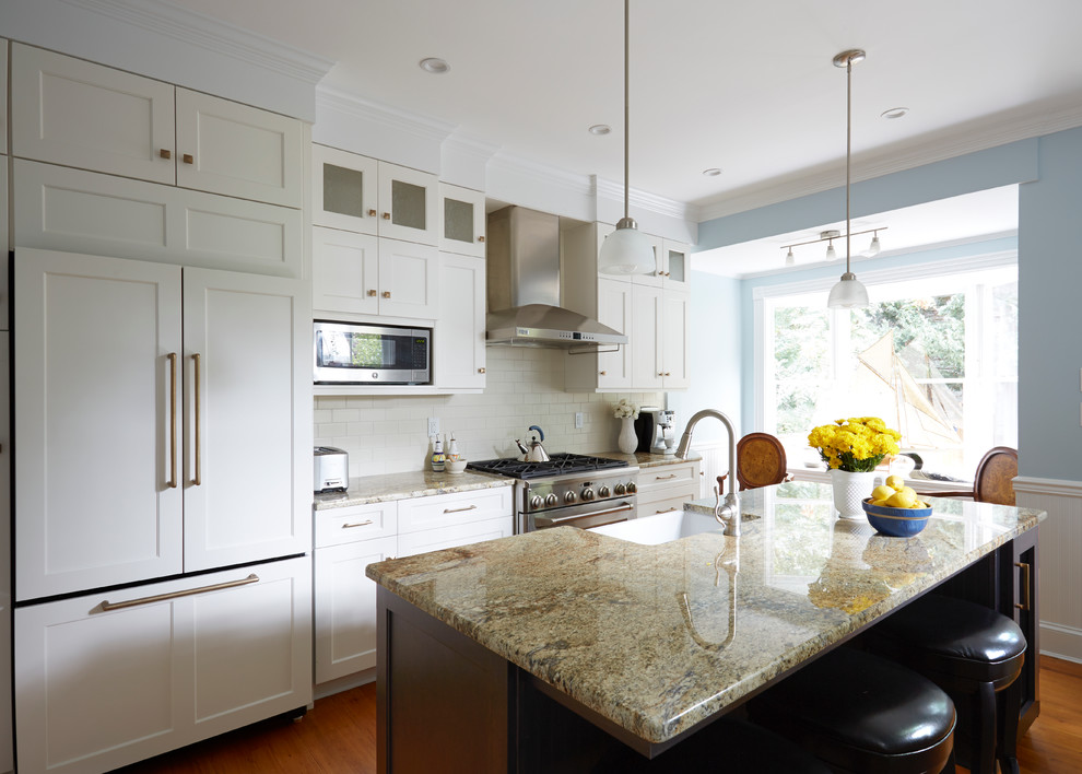 Eat-in kitchen - transitional medium tone wood floor eat-in kitchen idea in DC Metro with a farmhouse sink, recessed-panel cabinets, white cabinets, granite countertops, white backsplash, subway tile backsplash, stainless steel appliances and an island