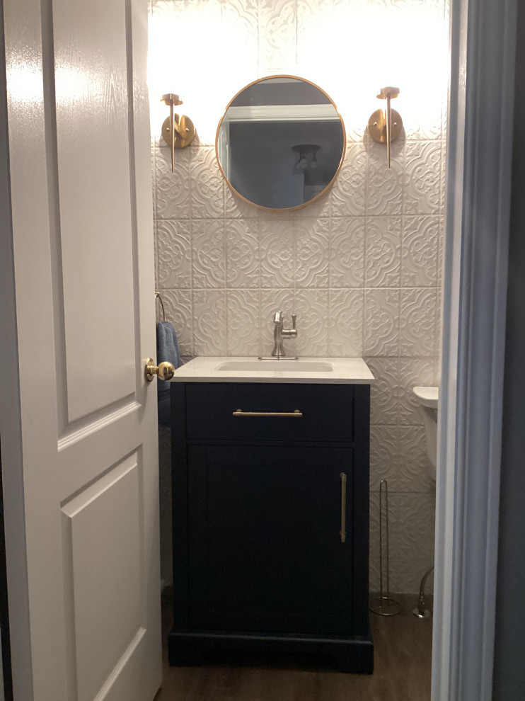 This is an example of a small country cloakroom in Ottawa with shaker cabinets, blue cabinets, a one-piece toilet, white tiles, ceramic tiles, white walls, laminate floors, a submerged sink, quartz worktops, brown floors, white worktops and a freestanding vanity unit.
