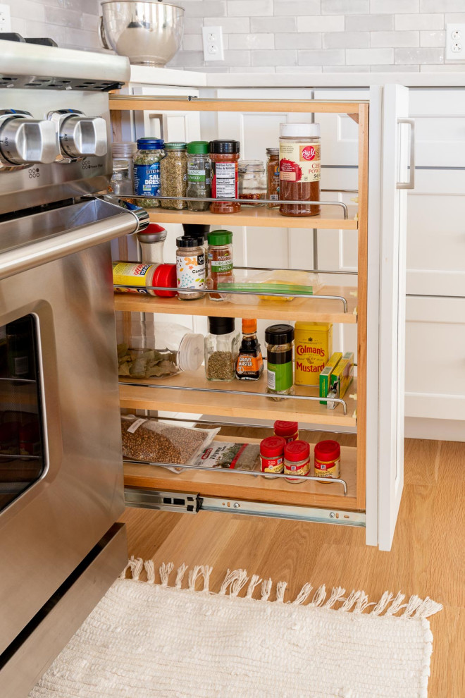 Inspiration for a huge transitional l-shaped light wood floor and brown floor open concept kitchen remodel in Boston with an undermount sink, shaker cabinets, white cabinets, quartz countertops, gray backsplash, subway tile backsplash, stainless steel appliances, an island and white countertops