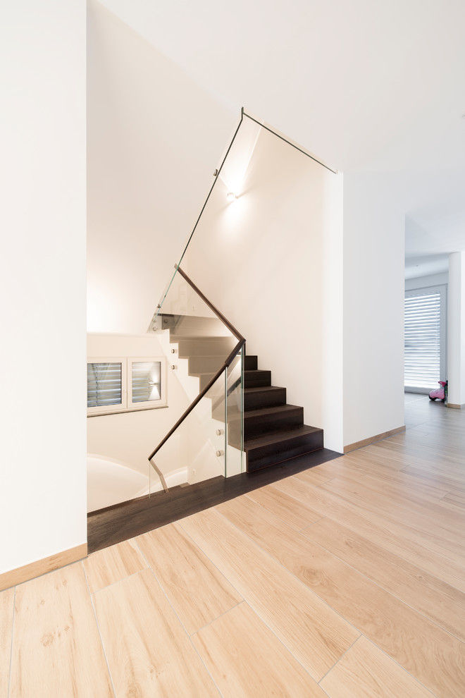 Inspiration for a mid-sized contemporary wood straight staircase in Munich with wood risers and glass railing.