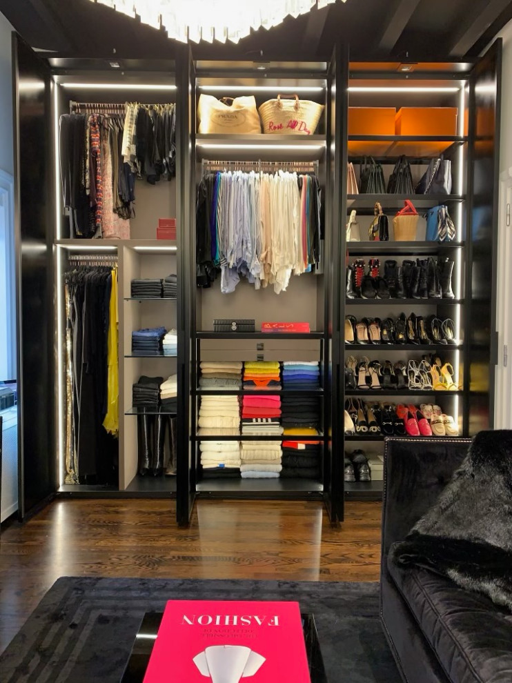 Photo of a large transitional women's dressing room in New York with glass-front cabinets and black cabinets.