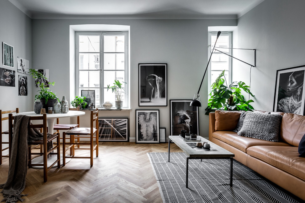 Scandinavian open concept living room in Stockholm with grey walls and medium hardwood floors.