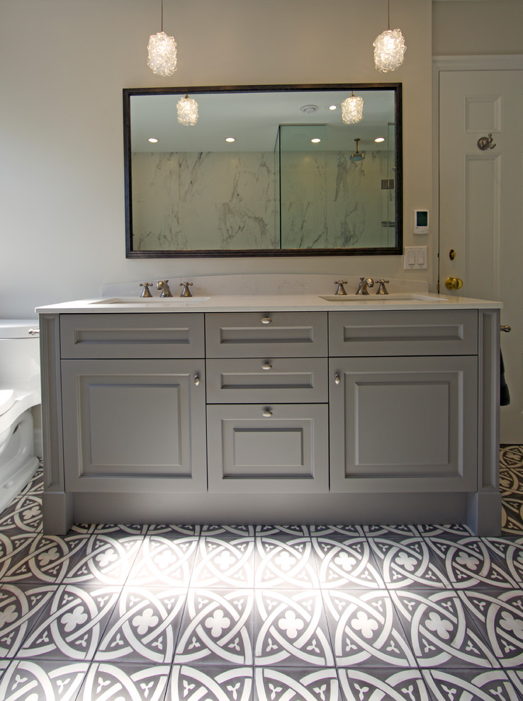 This is an example of a large transitional master bathroom in Toronto with raised-panel cabinets, grey cabinets, a drop-in tub, an alcove shower, a one-piece toilet, white tile, marble, beige walls, porcelain floors, an undermount sink and engineered quartz benchtops.