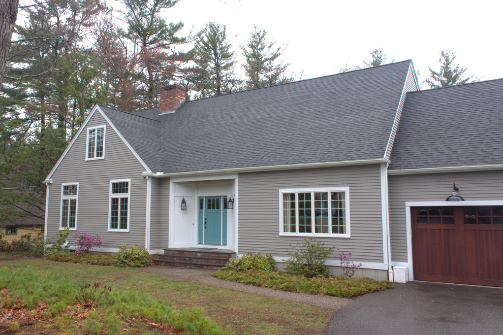 This is an example of a mid-sized transitional one-storey grey house exterior in Boston with vinyl siding, a gable roof and a shingle roof.