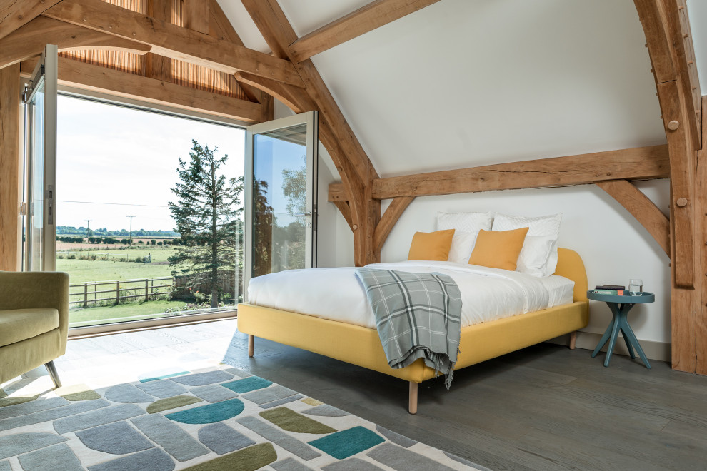 Design ideas for a country bedroom with white walls, medium hardwood flooring and brown floors.